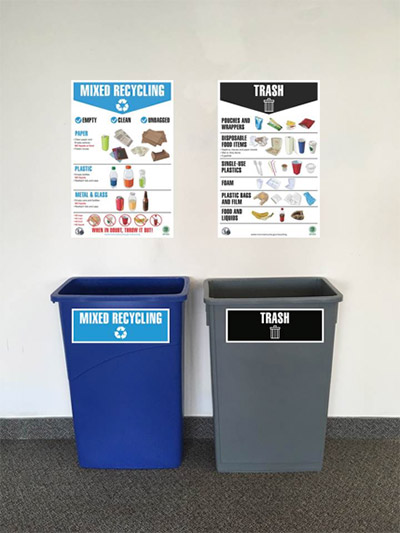 Office wall with Mixed Recycling sign over blue recycling bin and Trash sign over gray trash bin