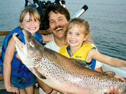 Picture or dad and two girls holding large fish.