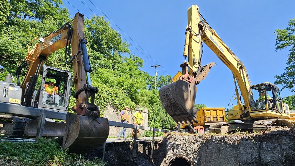 Photo of 2 construction excavators and workers working on a bridge