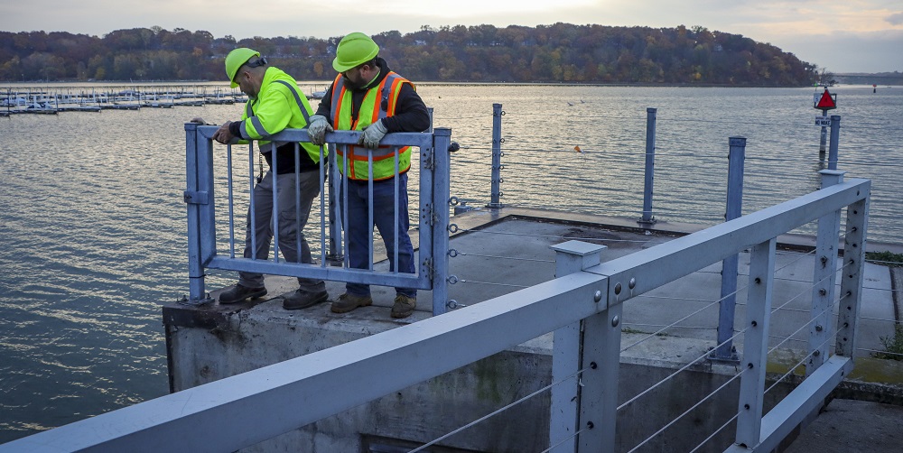 Photo of construction workers adding railing to a bridge over water