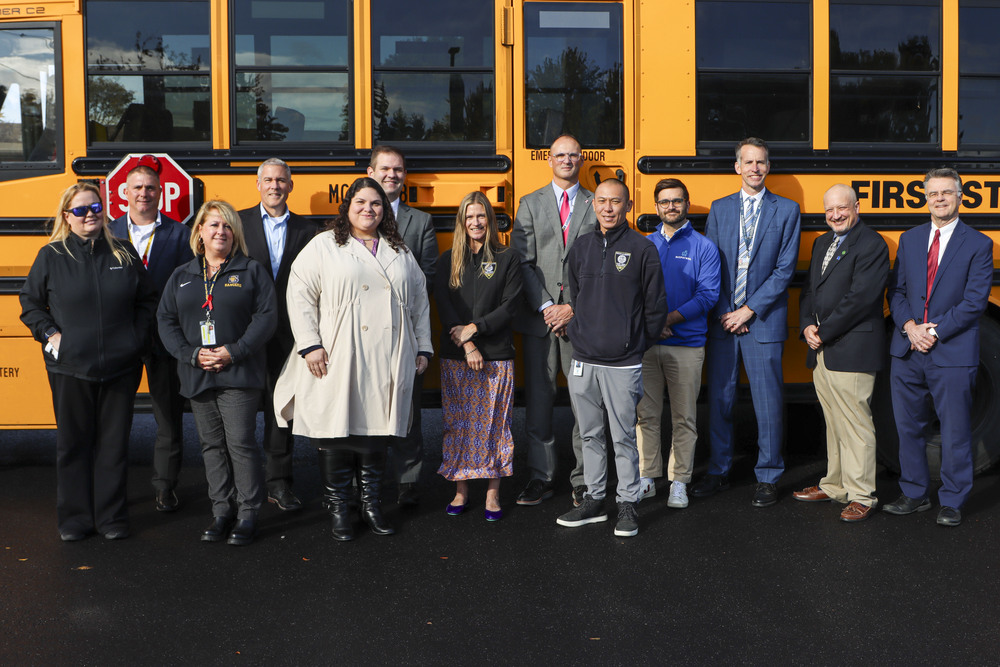 People from press conference in front of school bus