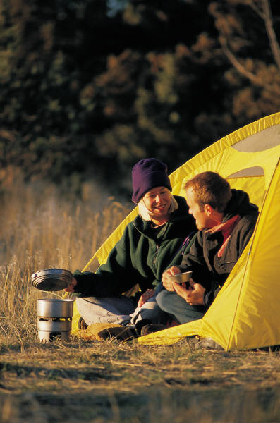 Two people cooking outside of thier tent 