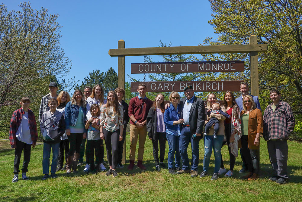A picture of Gary Beikirch, wife Lolly Beikirch, and extended family in front of Beikirch park sign